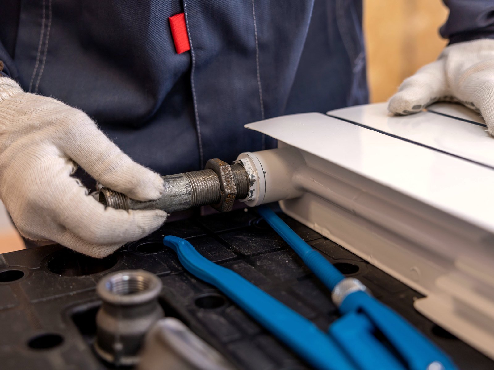Plumber fitting a radiator pipe with a hand tool